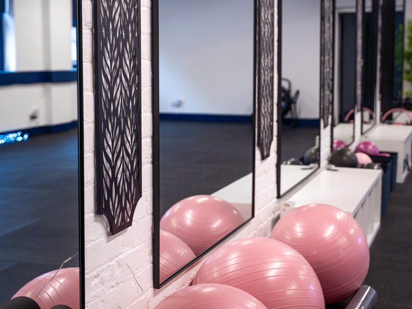 Pink stability balls lined up beneath the studio's tall mirrors and cut-out wall panels